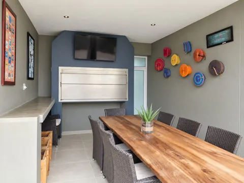 Moxie House — Covered outdoor braai and long wooden family dining table